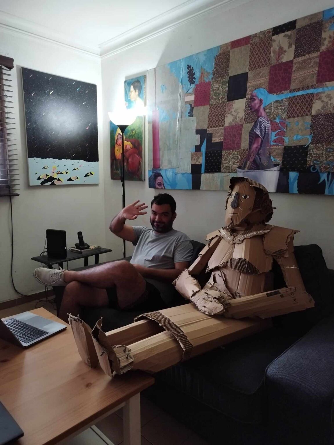 Tomás Pichardo sentado en sofá junto a estatua de cartón